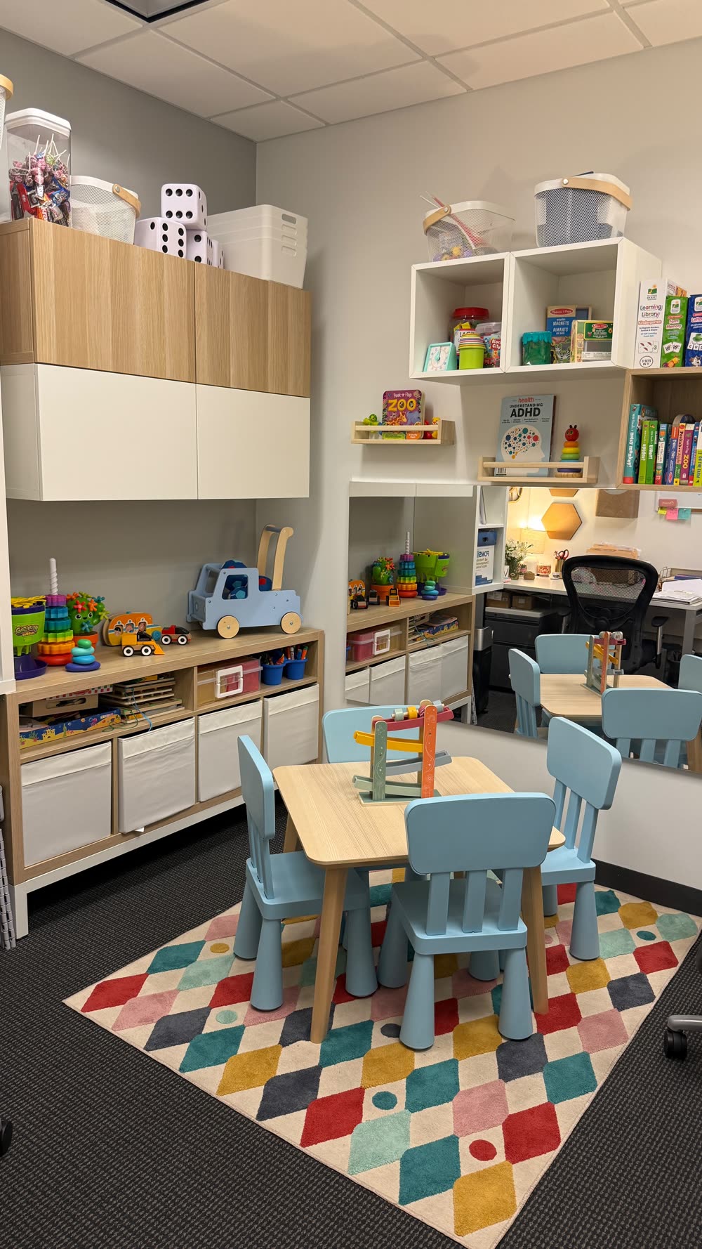 Therapy room with a child-size table, chairs and shelves of toys